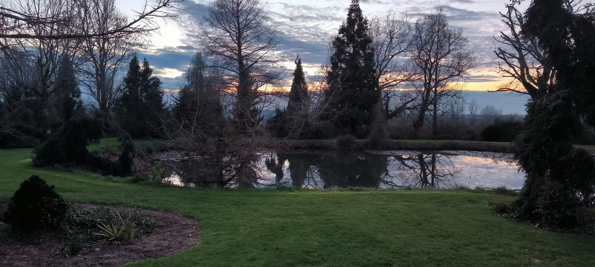 Le plan d'eau au crépuscule, reflétant les arbres de la rive